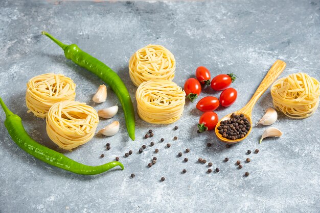 Spaghetti crudi nido con verdure su uno sfondo di marmo