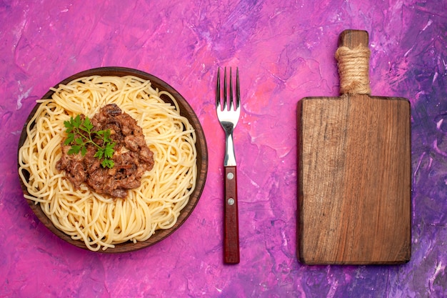 Spaghetti cucinati vista dall'alto con carne macinata su pasta di pasta di colore rosa da tavola