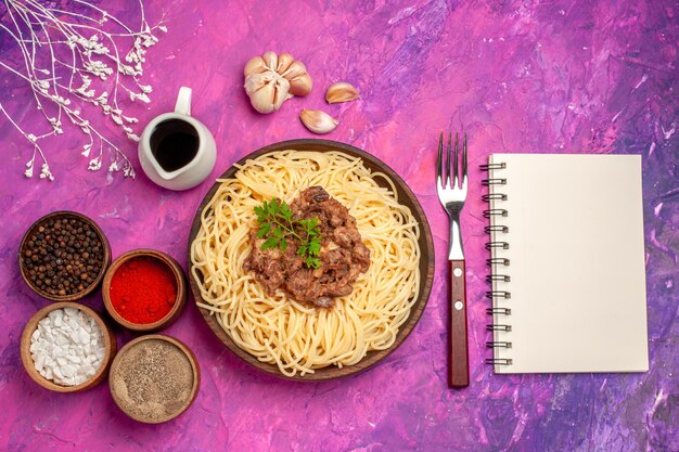 Spaghetti cucinati vista dall'alto con carne macinata su pasta rosa per condimenti da tavola