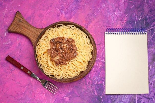 Spaghetti cucinati vista dall'alto con carne macinata sul condimento per piatti di pasta rosa da tavola