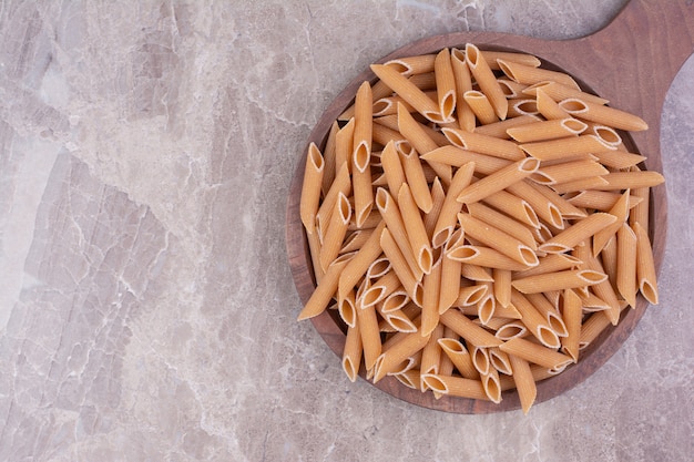 Spaghetti di forma a spirale in una tazza di legno rustica sul marmo