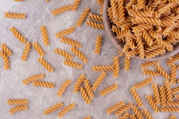 Spaghetti di forma a spirale in una tazza di legno rustica sul marmo