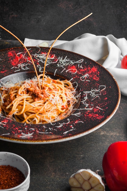 Spaghetti di vista laterale con carne tritata e aglio in zolla rotonda