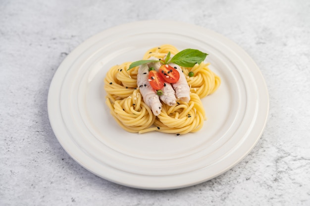 Spaghetti e maiale saltati in padella, splendidamente disposti in un piatto bianco.