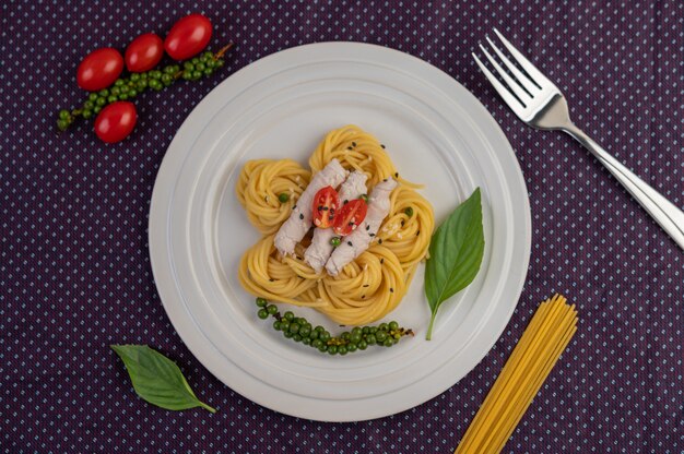 Spaghetti e maiale saltati in padella, splendidamente disposti in un piatto bianco.