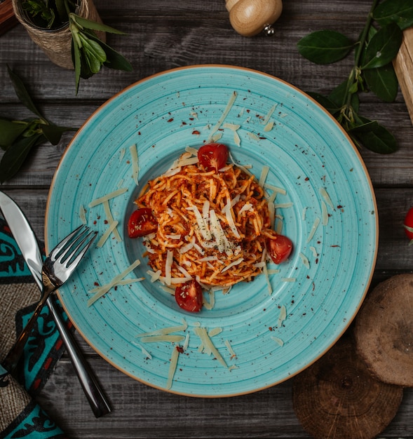 Spaghetti italiani in salsa al pomodoro con parmigiano all'interno del piatto blu, vista dall'alto.