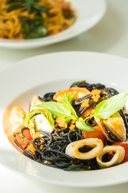 Spaghetti neri con frutti di mare in zolla bianca