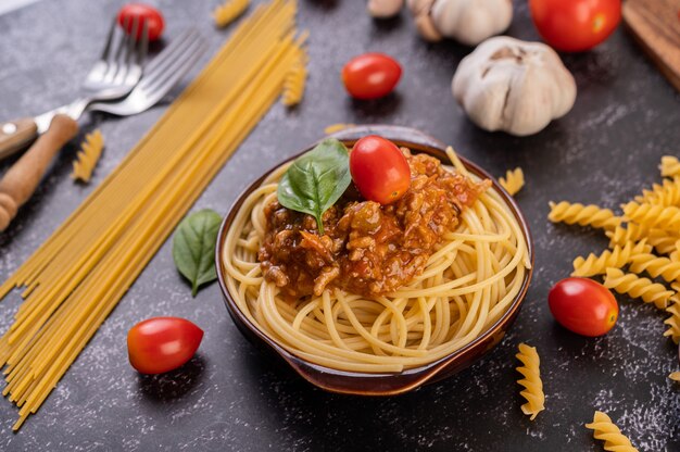 Spaghetti saltati in un piatto grigio con pomodori e basilico