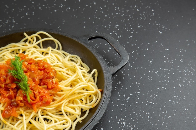 Spaghetti saporiti di vista di metà inferiore in padella sulla tavola nera