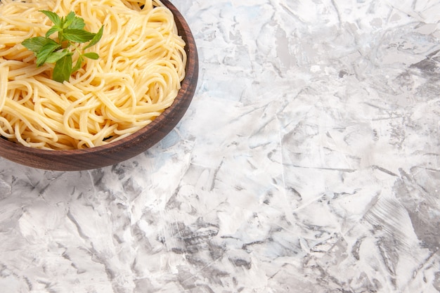 Spaghetti saporiti di vista frontale con la foglia verde sulla pasta bianca della pasta del piatto del pasto del pavimento