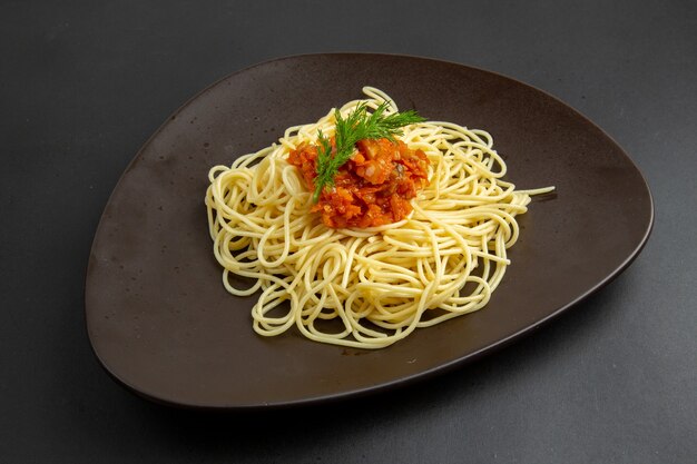 Spaghetti vista dal basso con salsa su piatto su sfondo nero