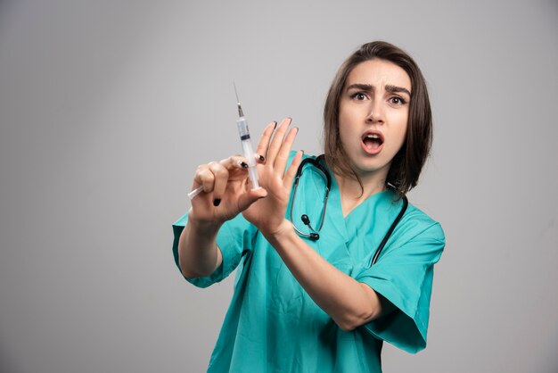 Spaventato medico in uniforme in posa con la siringa.