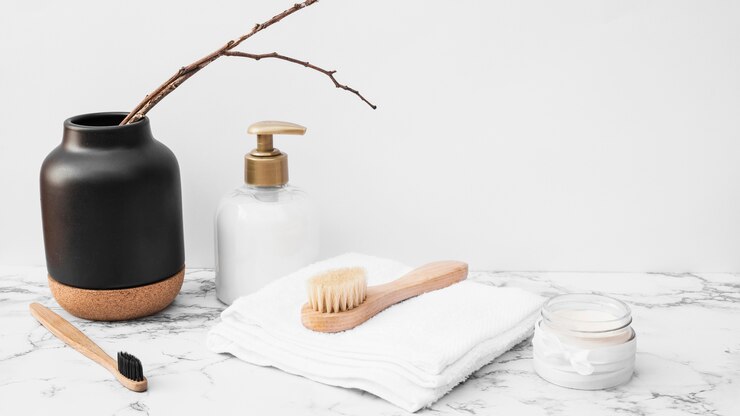 Foto gratuito spazzola; asciugamano; crema idratante e flacone cosmetico sulla superficie del marmo