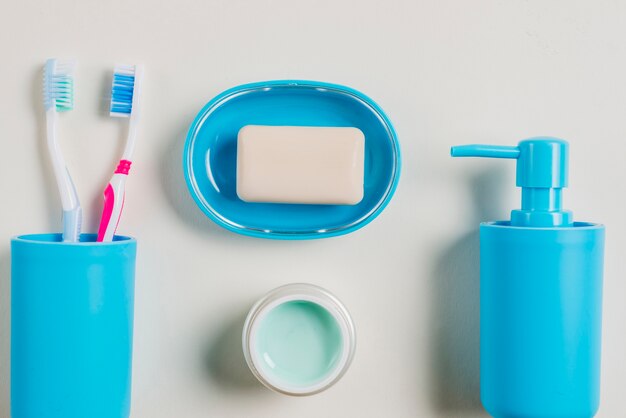 Spazzolini da denti; crema; distributore di sapone e sapone in contenitore blu con crema su priorità bassa bianca