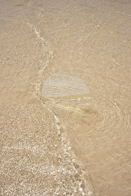 Specchio rotondo in vetro sulla spiaggia che riflette il paesaggio