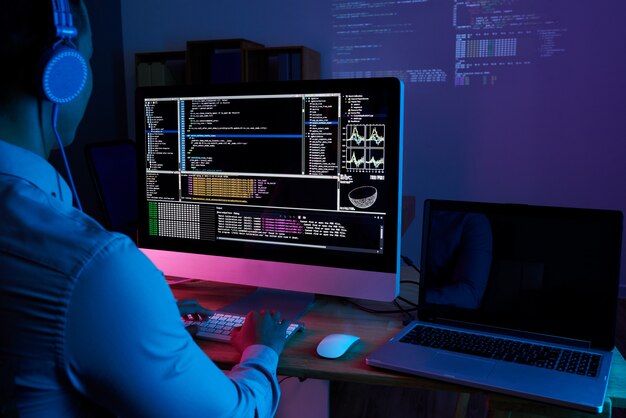 Specialista IT che controlla codice al computer nell'ufficio buio di notte