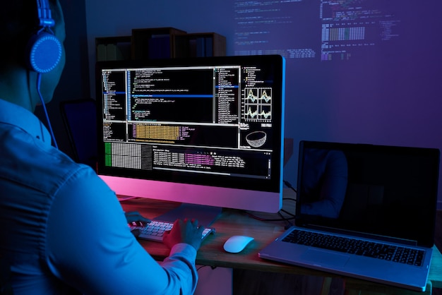 Specialista IT che controlla codice al computer nell'ufficio buio di notte