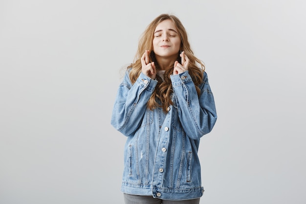 Speranzosa ragazza bionda sognante che esprime desiderio, dita incrociate buona fortuna