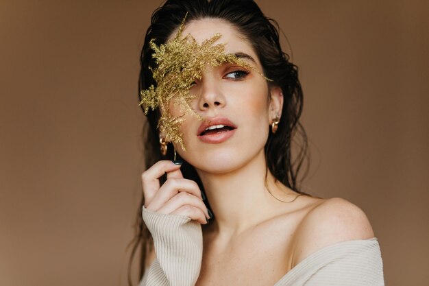 Spettacolare giovane donna con capelli neri che tiene fiore Romantica ragazza pallida in posa in studio con pianta