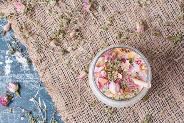 Spezie e petali con una tazza di bevanda sull'azzurro.