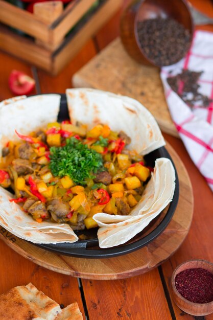 Spezzatino di manzo con patate e verdure tritate servite con lavash.