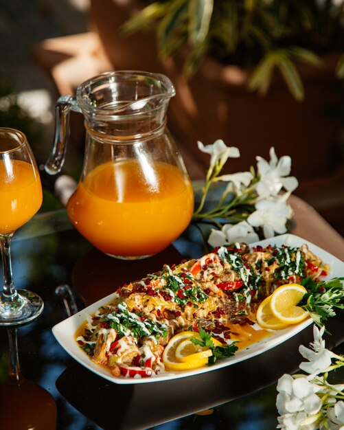 Spezzatino di verdure guarnito con erbe e limone, servito con succo d'arancia