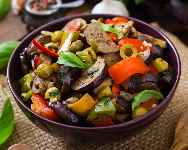 Spezzatino piccante speziato di melanzane, peperoni, olive e capperi con foglie di basilico.