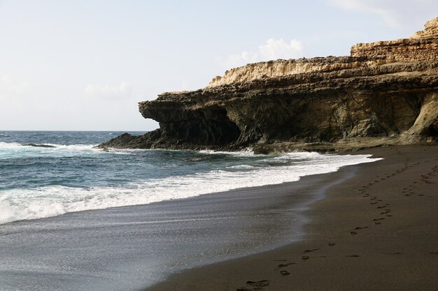 Spiaggia circondata da rocce e mare sotto la luce del sole nelle Isole Canarie