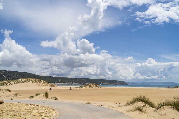 Spiaggia circondata dal mare e colline ricoperte di verde sotto un cielo nuvoloso in Andalusia, Spagna