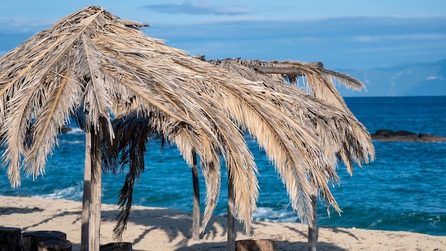 Spiaggia del Mar Egeo con ombrelloni fatti di rami di palma in Grecia