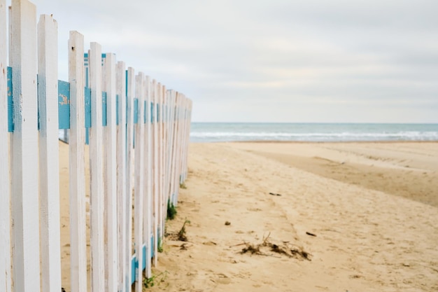 Spiaggia primaverile deserta, recinzione di fronte a una spiaggia pubblica, cielo nuvoloso in previsione della pioggia. Spiaggia di mare fuori stagione, luogo per il testo