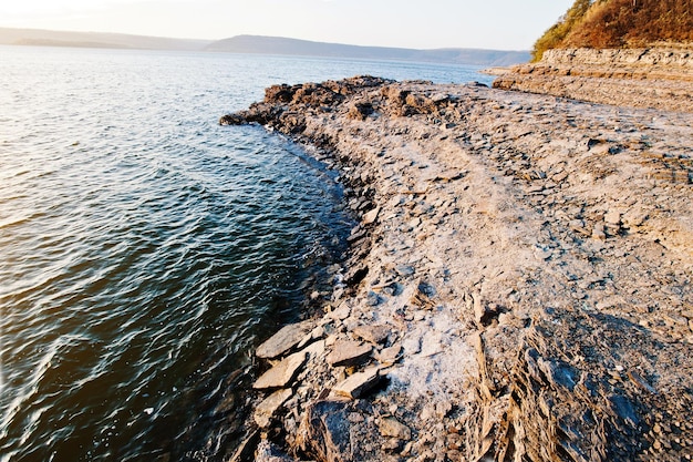 Spiaggia rocciosa del grande lago al tramonto