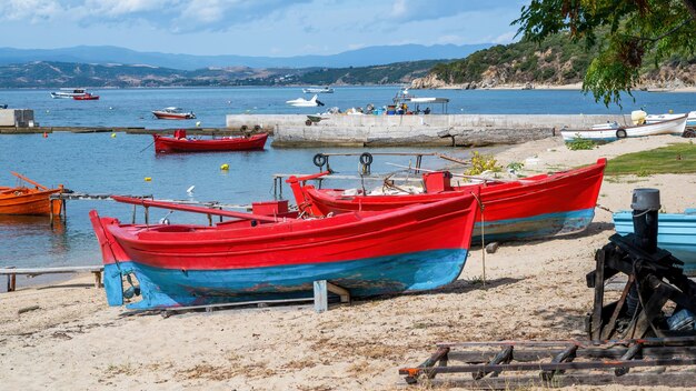 Spiaggiata barche colorate in legno sul costo del Mar Egeo, molo, yacht e colline a Ouranopoli, Grecia