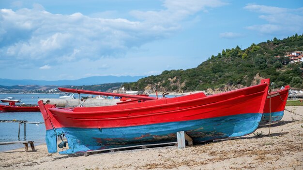 Spiaggiata barche colorate in legno sul costo del Mar Egeo, molo, yacht e colline a Ouranopoli, Grecia