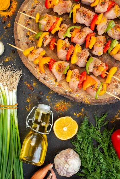 Spiedini di pollo crudo a metà vista dall'alto su bottiglia di olio di tavola di legno naturale al buio