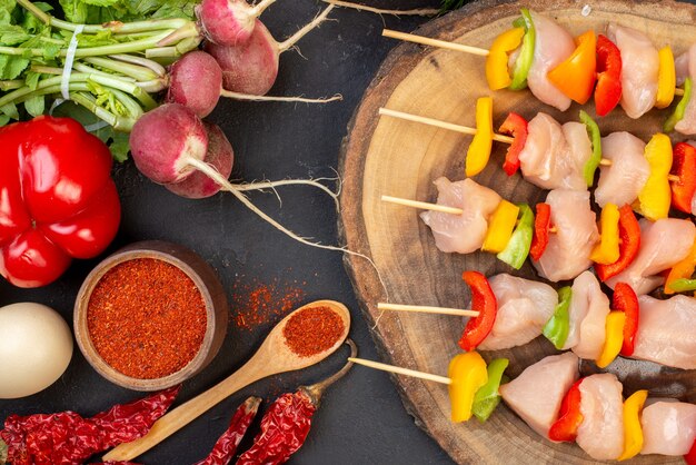 Spiedini di pollo crudo a metà vista dall'alto su tavola di legno naturale