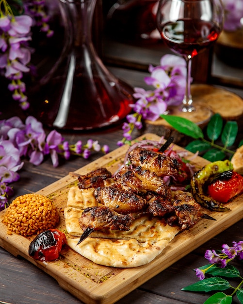 Spiedini di pollo su spiedini serviti con pane e verdure grigliate alla bulgur