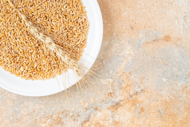 Spiga di grano e grano su un piatto, sul marmo.