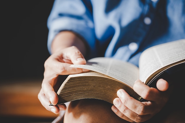 Spiritualità e religione, mani giunte in preghiera su una Sacra Bibbia nel concetto di chiesa per la fede.