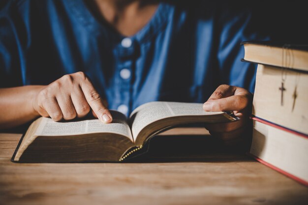 Spiritualità e religione, mani giunte in preghiera su una Sacra Bibbia nel concetto di chiesa per la fede.