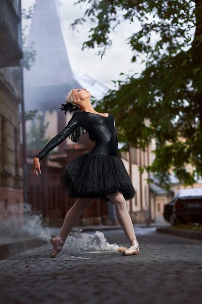 Splendida ballerina in abito nero che balla per le strade della città