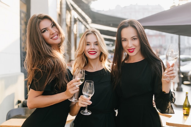 Splendida donna elegante con i capelli lunghi neri, trascorrere del tempo con le sorelle in città