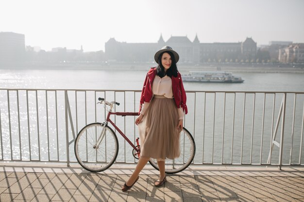 Splendida donna in abiti vintage in posa con piacere vicino al fiume