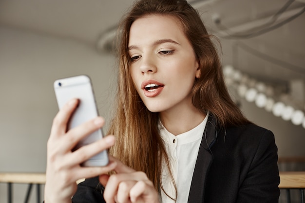 Splendida giovane donna utilizzando il telefono cellulare in uno spazio di co-working