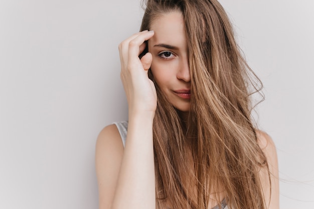 Splendida ragazza bianca in posa con l'espressione del viso calma. Ritratto dell'interno di incredibile modello femminile con i capelli lunghi isolati.