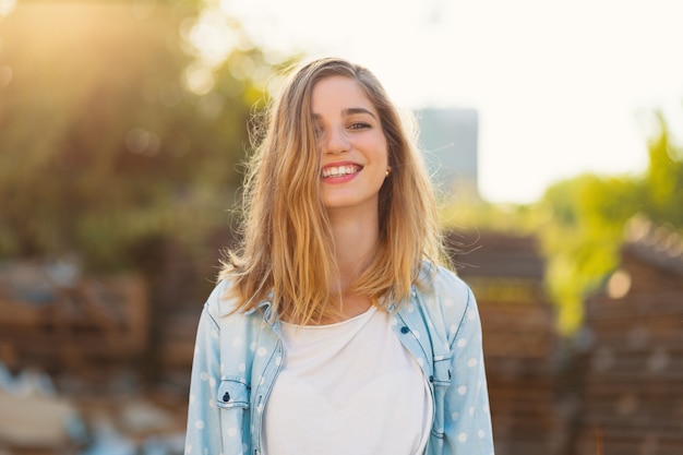 Splendida ragazza con un bel sorriso e raggi di sole riflessa sul suo viso felice