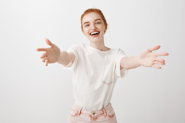 Splendida ragazza rossa che raggiunge le mani in avanti per un abbraccio