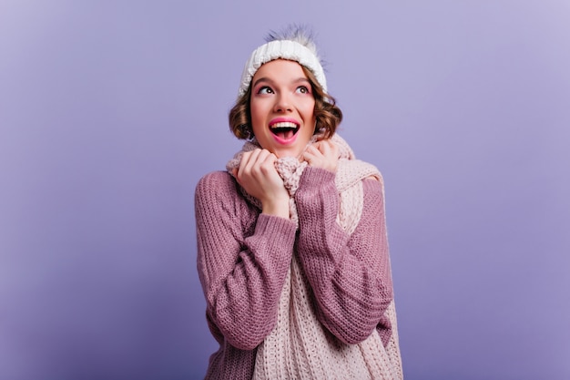 Splendido modello femminile che esprime emozioni felici durante il servizio fotografico in abiti invernali. Ritratto dell'interno di bella ragazza con taglio di capelli alla moda indossa un maglione morbido.