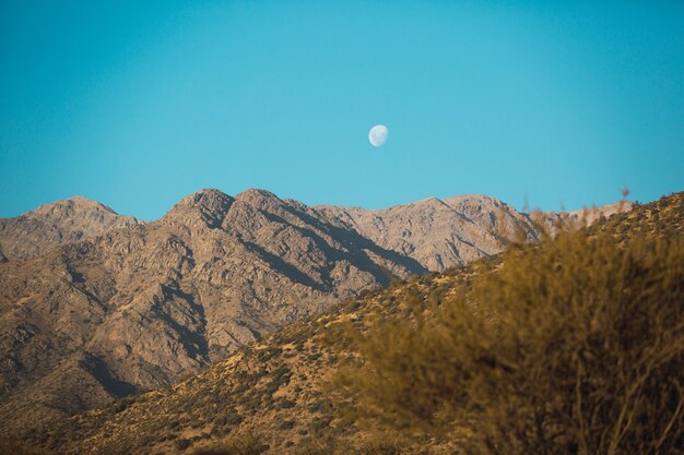 Splendido scenario di una catena montuosa al tramonto e la luna fuori