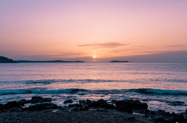 Splendido scenario di una spiaggia rocciosa e un mare durante il tramonto